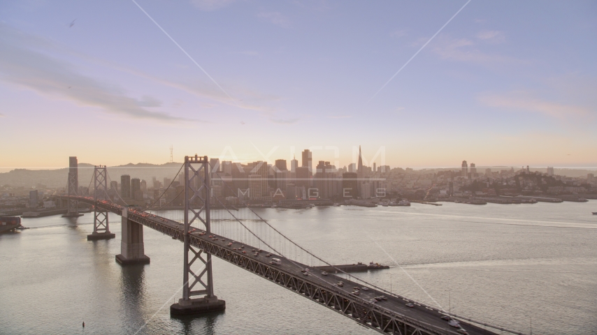 The Bay Bridge with a view of Downtown San Francisco skyline, California, twilight Aerial Stock Photo DCSF07_070.0000279 | Axiom Images
