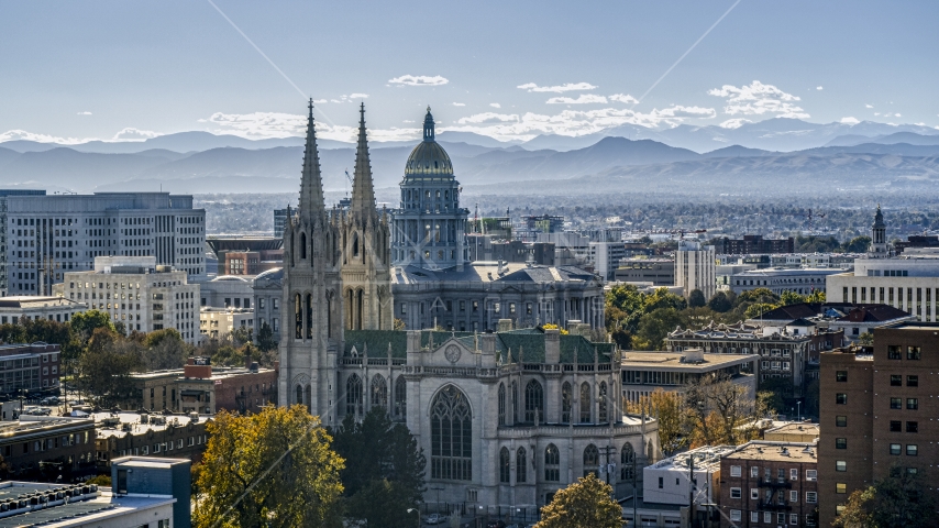 A cathedral and Colorado State Capitol dome with mountains in the distance, Downtown Denver, Colorado Aerial Stock Photo DXP001_000170 | Axiom Images