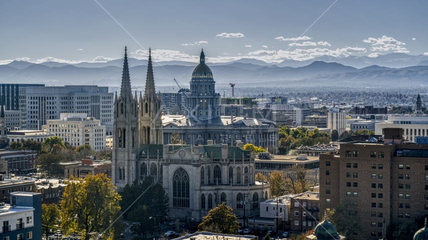 A cathedral and Colorado State Capitol dome with mountains in the background, Downtown Denver, Colorado Aerial Stock Photo DXP001_000171 | Axiom Images