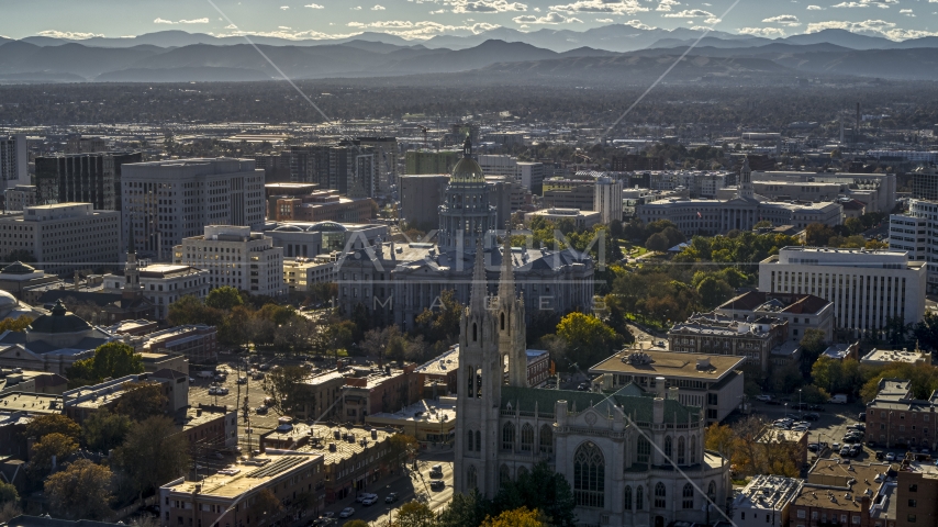 The Colorado State Capitol building behind a cathedral, mountains in background, Downtown Denver, Colorado Aerial Stock Photo DXP001_000175 | Axiom Images