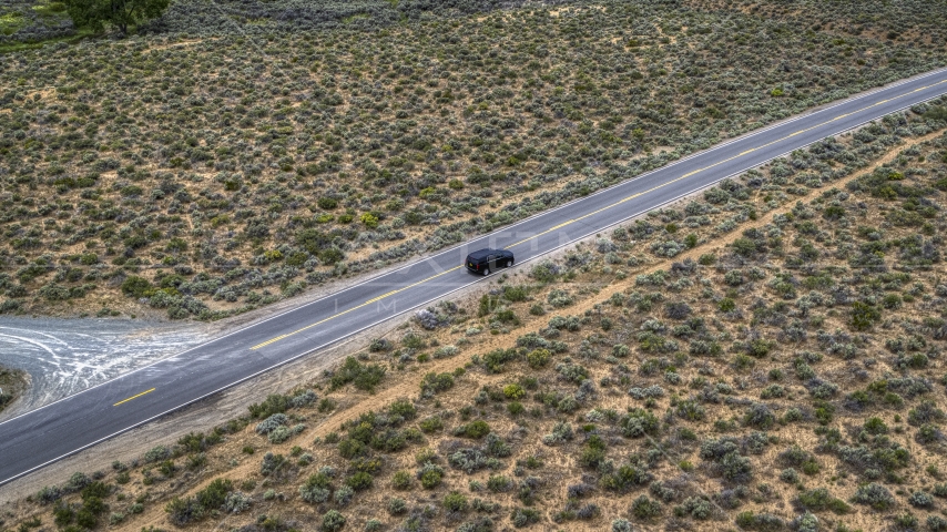 A black SUV parked on the side of a desert road in Carson City, Nevada Aerial Stock Photo DXP001_007_0003 | Axiom Images