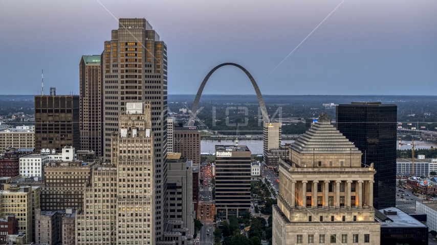 A view of the Gateway Arch between a skyscraper and a courthouse at twilight, Downtown St. Louis, Missouri Aerial Stock Photo DXP001_036_0011 | Axiom Images