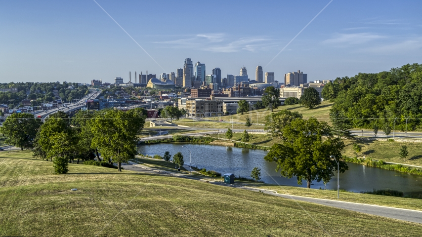 A view of the city's skyline from green grass beside a small lake in Kansas City, Missouri Aerial Stock Photo DXP001_045_0006 | Axiom Images