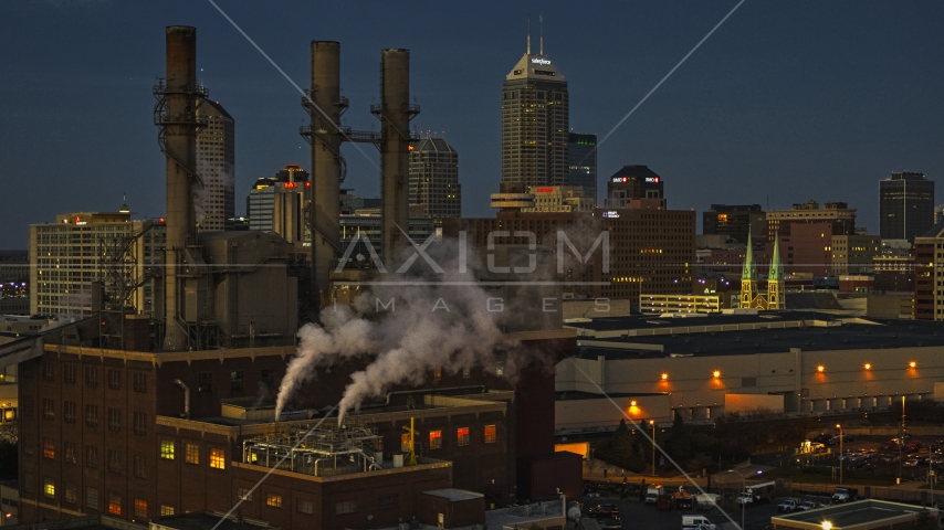 Factory smoke stacks with view of the city skyline at twilight, Downtown Indianapolis, Indiana Aerial Stock Photo DXP001_093_0003 | Axiom Images