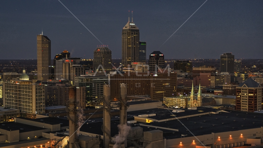 Giant skyscrapers of the city skyline at twilight, seen from smoke stacks, Downtown Indianapolis, Indiana Aerial Stock Photo DXP001_093_0005 | Axiom Images