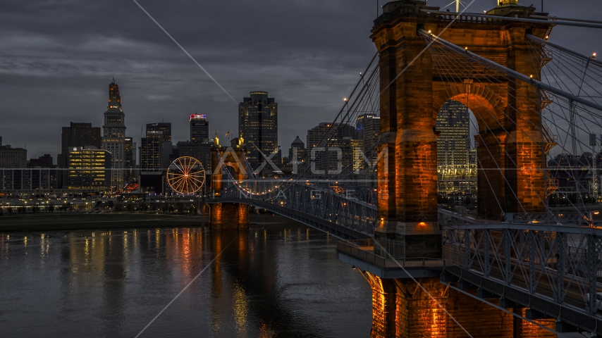 The city skyline behind Roebling Bridge lit up at twilight, seen from Ohio River, Downtown Cincinnati, Ohio Aerial Stock Photo DXP001_098_0003 | Axiom Images