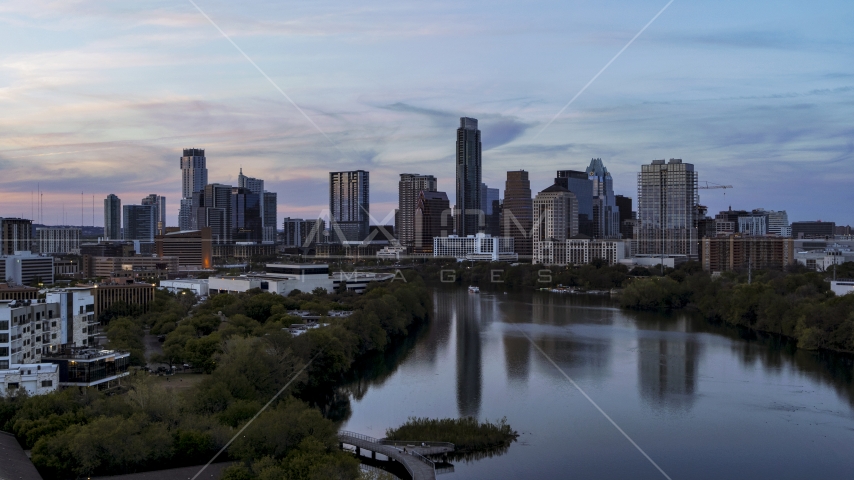 The city's waterfront skyline seen from low over Lady Bird Lake at twilight in Downtown Austin, Texas Aerial Stock Photo DXP002_110_0011 | Axiom Images