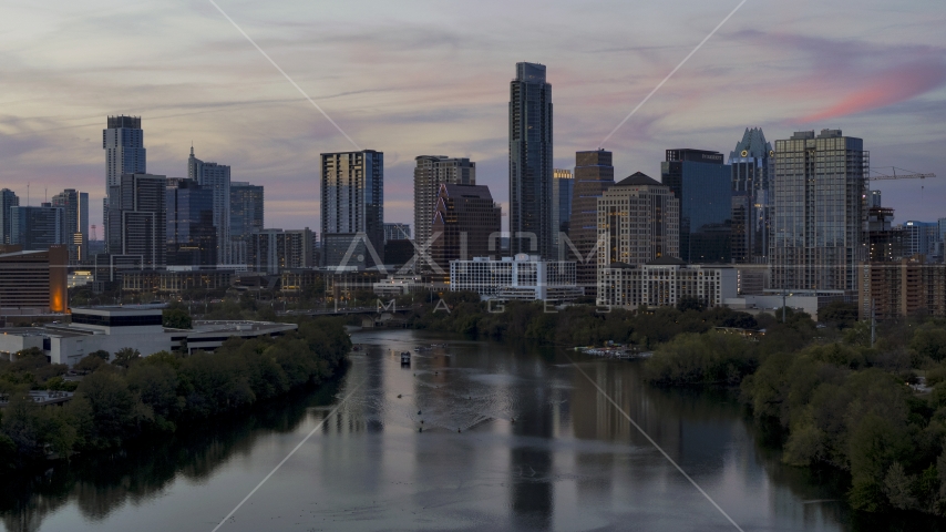 A view of the tall Austonian skyscraper and city skyline seen fro, over Lady Bird Lake at twilight in Downtown Austin, Texas Aerial Stock Photo DXP002_110_0012 | Axiom Images