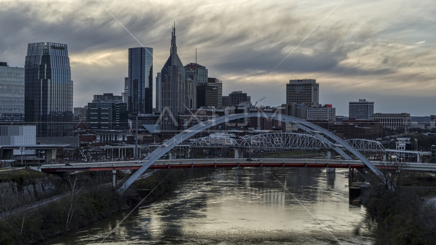 A view of riverfront skyline near a bridge and the Cumberland River at sunset, Downtown Nashville, Tennessee Aerial Stock Photo DXP002_120_0004 | Axiom Images