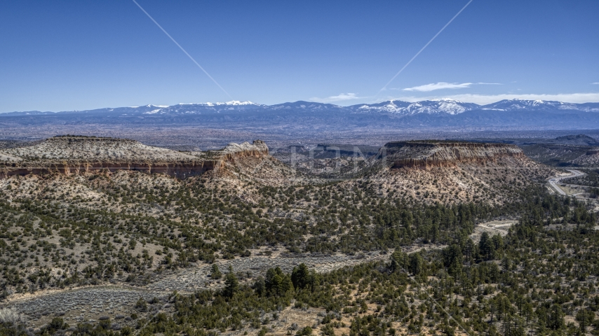 Flat desert mesas and mountains in the background in New Mexico Aerial Stock Photo DXP002_133_0012 | Axiom Images