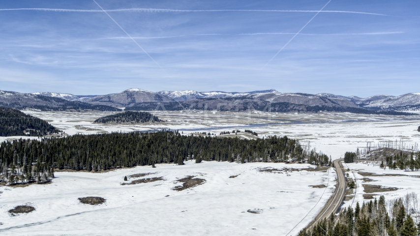 A view of distant mountains on the other side of a snowy valley, New Mexico Aerial Stock Photo DXP002_134_0008 | Axiom Images