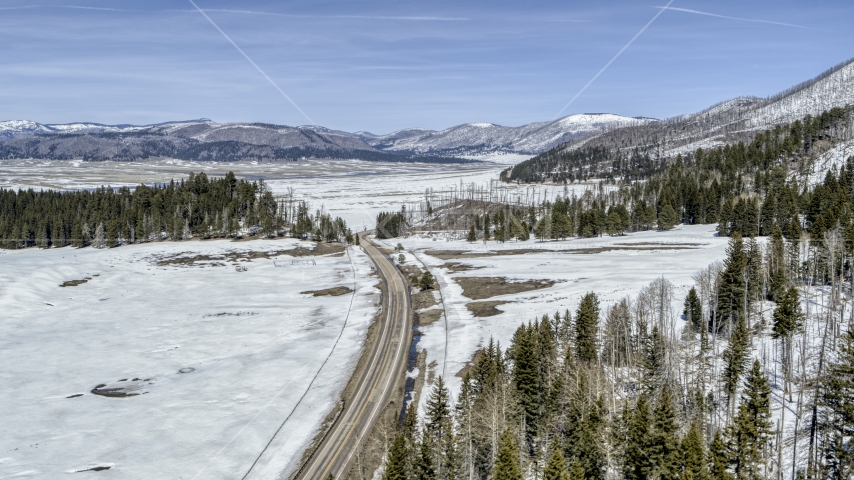 A country road in snowy valley with view of mountains, New Mexico Aerial Stock Photo DXP002_134_0010 | Axiom Images