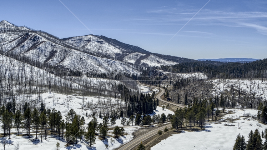 A winding road by snowy mountains, New Mexico Aerial Stock Photo DXP002_134_0014 | Axiom Images