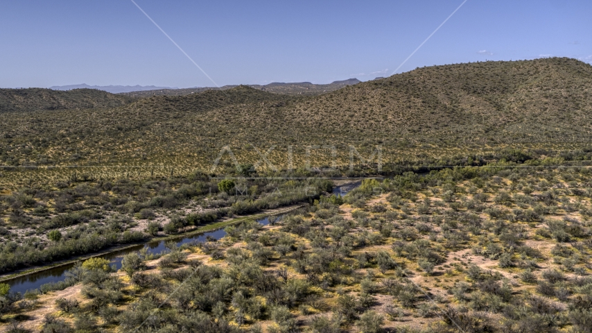 A narrow river through the desert near a hill Aerial Stock Photo DXP002_141_0022 | Axiom Images