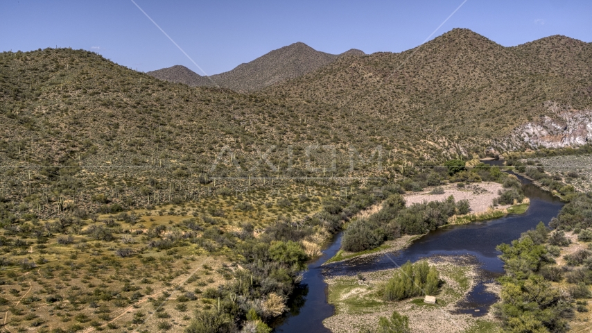 A shallow river bordered by desert hills with cactus Aerial Stock Photo DXP002_141_0024 | Axiom Images