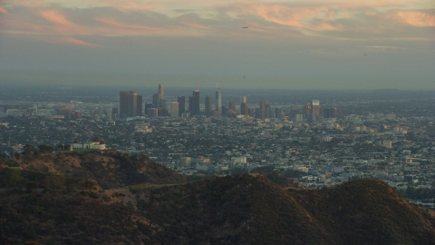 AX0162_105.0000154 - Aerial stock photo of The skyline of Downtown Los Angeles, California at twilight and Griffith Observatory