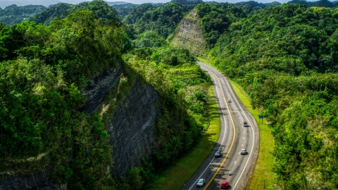 AX101_078.0000299F - Aerial stock photo of Light highway  traffic through lush green mountains, Karst Forest, Puerto Rico 