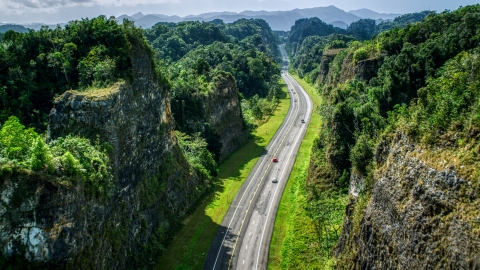 AX101_084.0000123F - Aerial stock photo of Light traffic on a highway through lush green mountains, Karst Forest, Puerto Rico