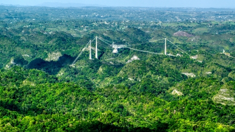 AX101_087.0000000F - Aerial stock photo of Arecibo Observatory rising above the lush green Karst Forest, Puerto Rico 