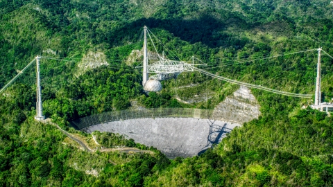 AX101_090.0000342F - Aerial stock photo of The dish of the Arecibo Observatory among lush green jungle, Puerto Rico 