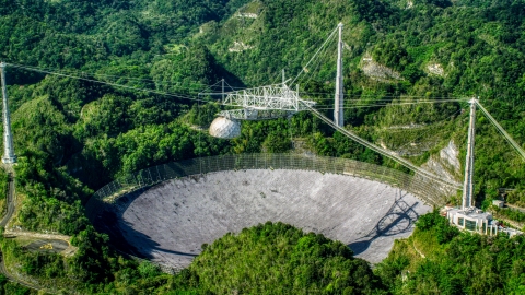 AX101_092.0000000F - Aerial stock photo of Arecibo Observatory nestled in the lush green forest, Puerto Rico 