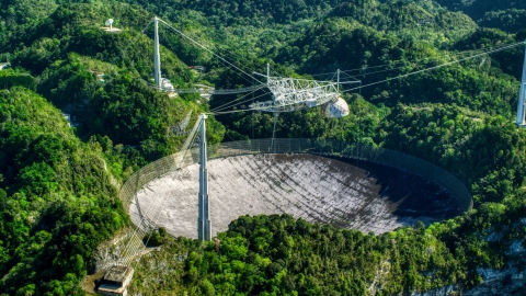 AX101_098.0000000F - Aerial stock photo of The Arecibo Observatory surrounded by trees, Puerto Rico