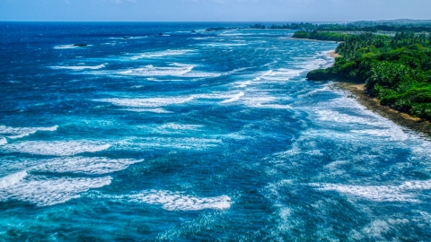 AX101_198.0000000F - Aerial stock photo of Ocean waves rolling toward a Caribbean island coast in Vega Baja, Puerto Rico