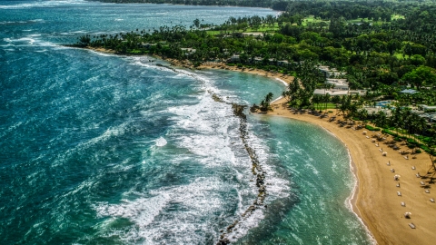 AX101_214.0000000F - Aerial stock photo of Waves hitting the breakwater by a Caribbean beach resort in Dorado, Puerto Rico 