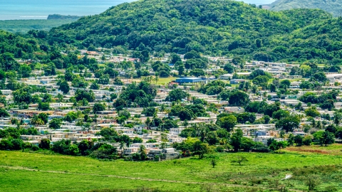 AX102_055.0000000F - Aerial stock photo of Homes beside tree covered hills, Fajardo, Puerto Rico 