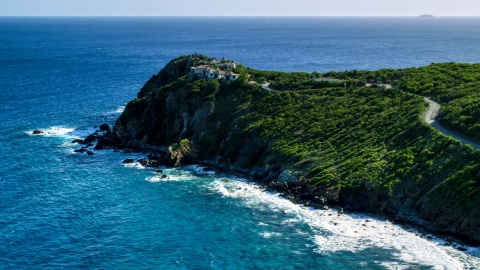 AX103_043.0000356F - Aerial stock photo of Cliff top mansion among trees and sapphire blue Caribbean waters, Cruz Bay, St John
