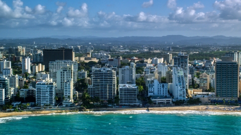 AX103_150.0000114F - Aerial stock photo of Beachfront condo complexes along Caribbean blue waters, San Juan, Puerto Rico