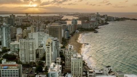 AX104_068.0000000F - Aerial stock photo of Beachfront hotels and ocean waters, San Juan, Puerto Rico, sunset