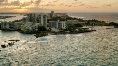AX104_072.0000000F - Aerial stock photo of The oceanfront Caribe Hilton Hotel and Normandie Hotel, San Juan, Puerto Rico, sunset
