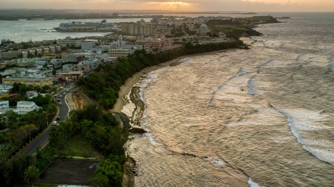 AX104_075.0000083F - Aerial stock photo of Caribbean buildings near the beach and ocean, Old San Juan, Puerto Rico, sunset