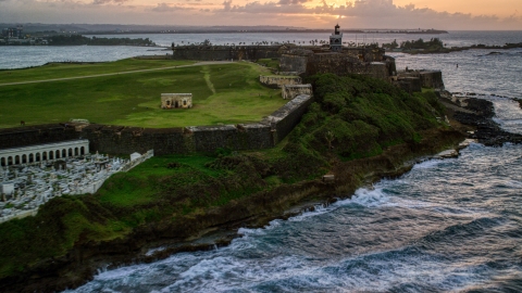 AX104_080.0000107F - Aerial stock photo of Fort San Felipe del Morro and lighthouse, Old San Juan, sunset