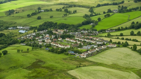 AX109_003.0000117F - Aerial stock photo of Rural homes surrounded by green fields, Banton, Scotland