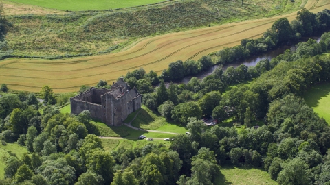 AX109_066.0000137F - Aerial stock photo of Historic Doune Castle beside a river in Scotland