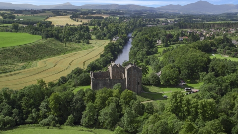 AX109_076.0000000F - Aerial stock photo of Doune Castle and River Teith lined with trees, Scotland