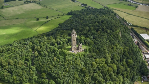 AX109_100.0000008F - Aerial stock photo of The historic Wallace Monument surrounded by trees on Abbey Craig hill in Stirling, Scotland