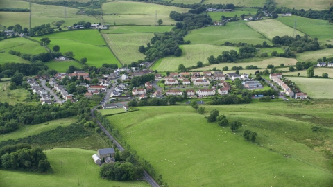 AX110_233.0000280F - Aerial stock photo of Rural homes surrounded by farmland in Cumbernauld, Scotland