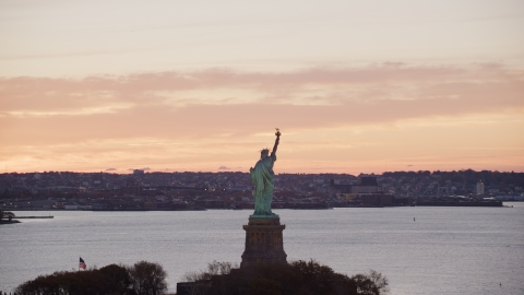 AX118_041.0000196F - Aerial stock photo of Statue of Liberty with a view of Brooklyn at sunrise, New York