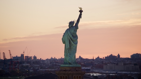 AX118_042.0000234F - Aerial stock photo of Behind the Statue of Liberty at sunrise, New York