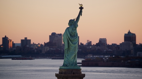 AX118_044.0000000F - Aerial stock photo of Statue of Liberty, and Brooklyn across the harbor at sunrise, New York