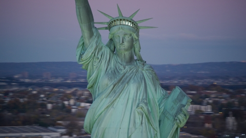 AX118_059.0000153F - Aerial stock photo of Statue of Liberty at sunrise, purple sky overhead, New York