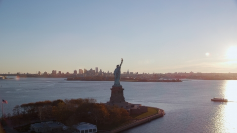 AX118_118.0000187F - Aerial stock photo of Statue of Liberty and Brooklyn across the harbor at sunrise in New York