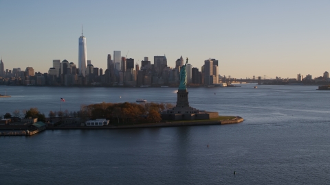 AX118_122.0000000F - Aerial stock photo of Statue of Liberty and Lower Manhattan skyline at sunrise in New York