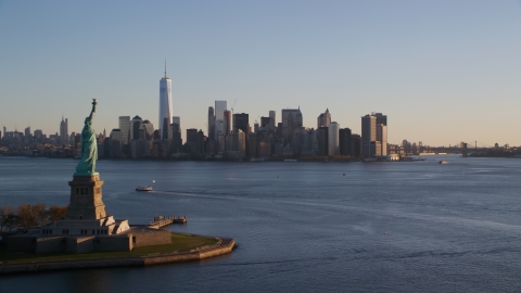 AX118_122.0000202F - Aerial stock photo of The Statue of Liberty and Lower Manhattan skyline at sunrise in New York