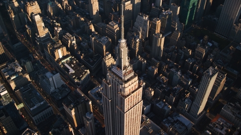 AX118_182.0000195F - Aerial stock photo of Empire State Building and spire at sunrise in Midtown Manhattan, New York City