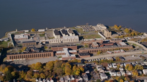 AX119_114.0000314F - Aerial stock photo of Sing Sing Prison by the Hudson River in Autumn, Ossining, New York