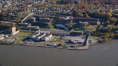 AX119_122.0000128F - Aerial stock photo of Sing Sing Prison by the Hudson River in Autumn, Ossining, New York